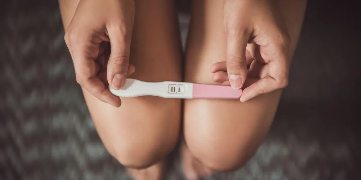 Closeup of a woman holding a positive pregnancy test. 
