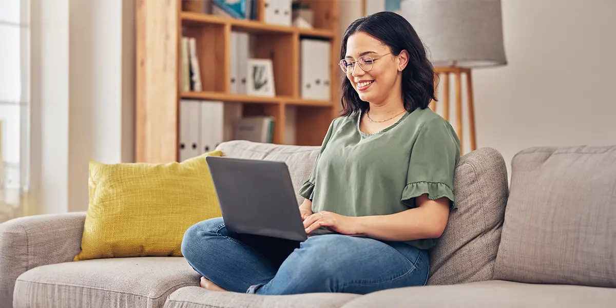 Young woman smiling while using her laptop.