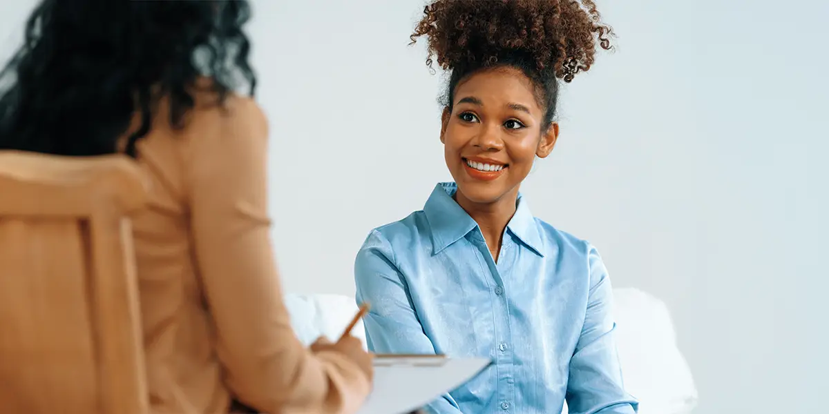 Young Black woman smiling talking to a professional during a consultation. 