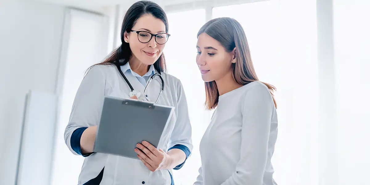 Caucasian female doctor showing her young female patient medical documents.