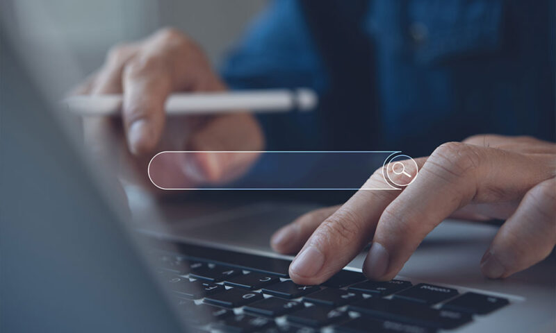 Closeup of man’s hands searching on a computer screen. 