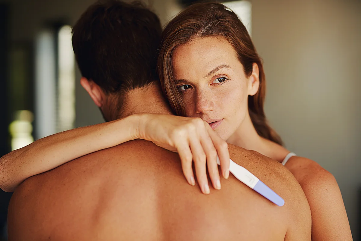 Attractive caucasian woman holding a pregnancy test and hugging her partner