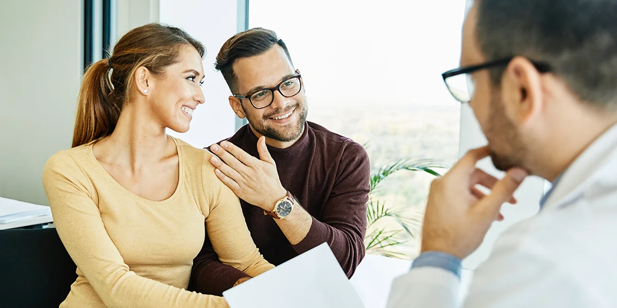 Happy couple talking to a male doctor