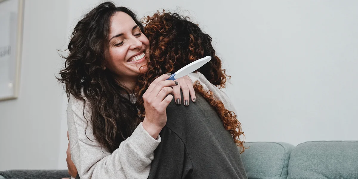 Happy lesbian couple holding a pregnancy test