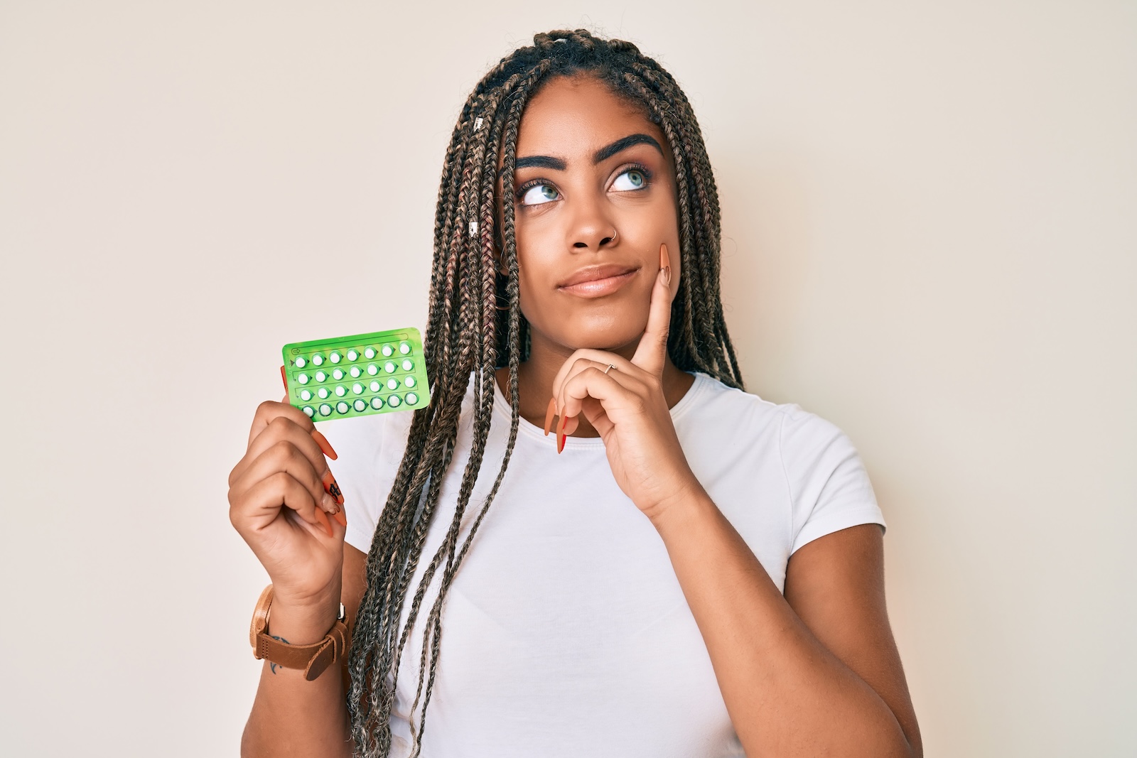 Young Black woman holding up a pack of birth control pills