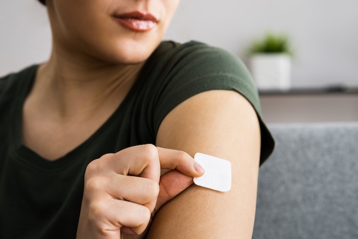 Ethnically ambiguous young woman putting on a birth control patch