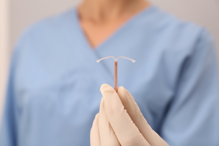 Doctor in scrubs holding up a copper IUD