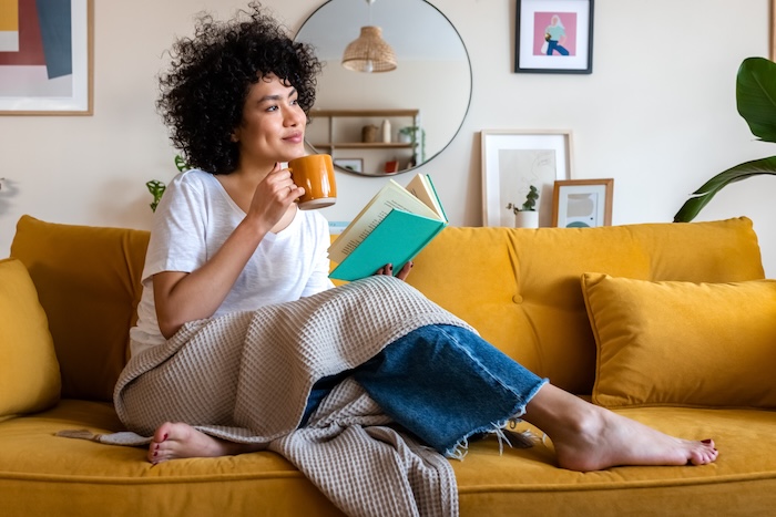Ethnically ambiguous young woman reading on a sofa at home