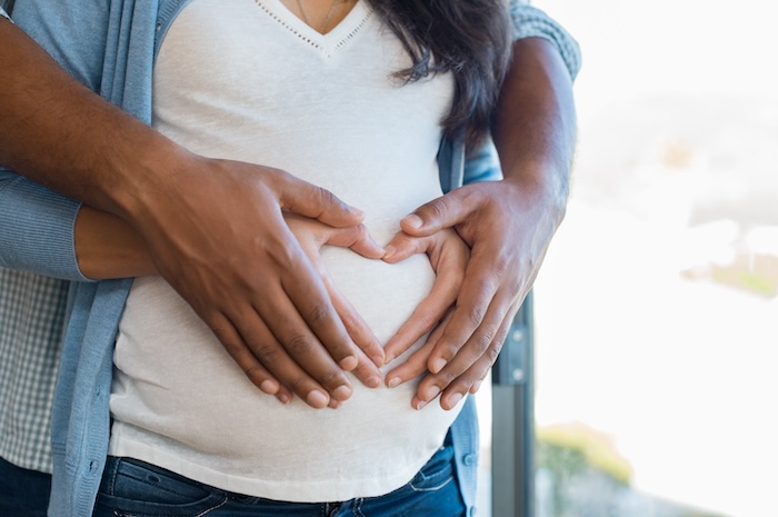 Mixed-race couple hugging the woman’s pregnant belly