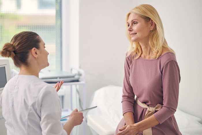 Middle-aged blonde woman talking to a female medical professional
