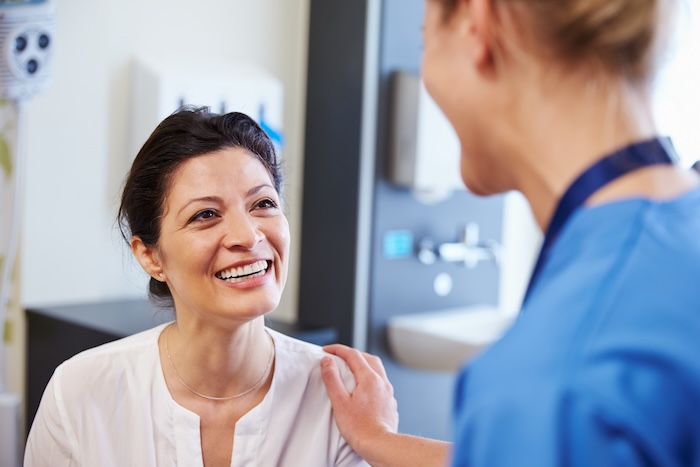 Middle-aged latina woman smiling while talking to a female doctor