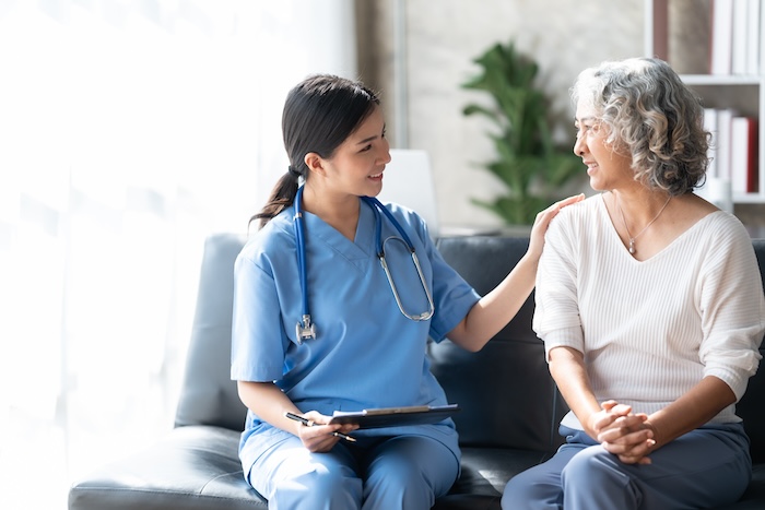Mature asian woman talking to a young woman medical professional