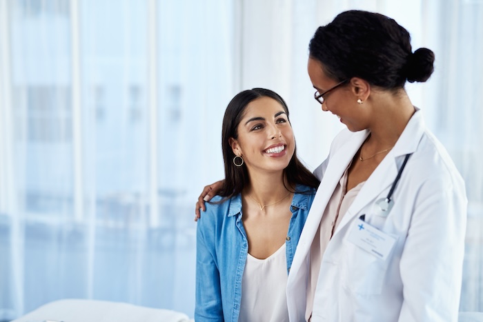 Black female doctor hugging her young female egg donor patient