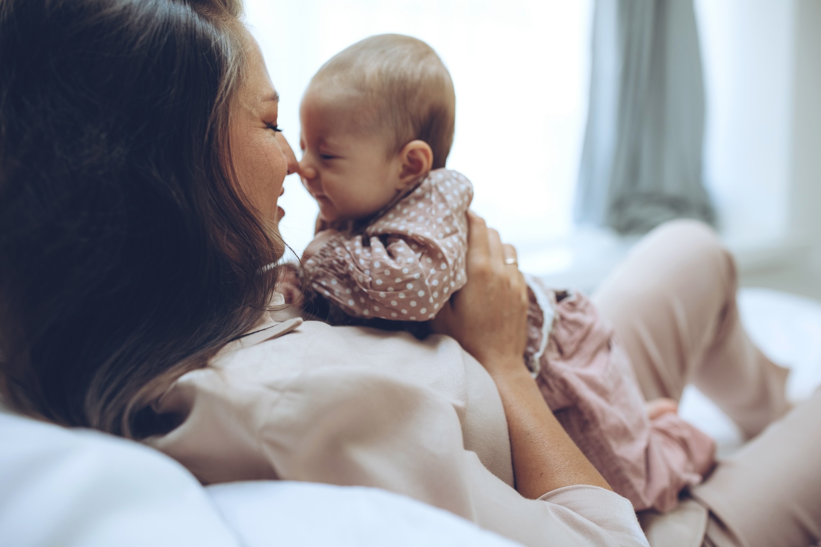 Caucasian mom touching noses with her newborn baby