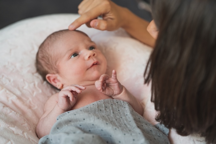 New mom touching the head of her newborn baby