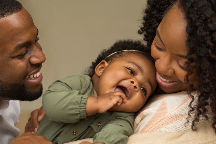 Black parents laughing and holding their baby girl