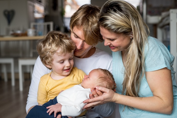 Caucasian parents with their young son and new baby