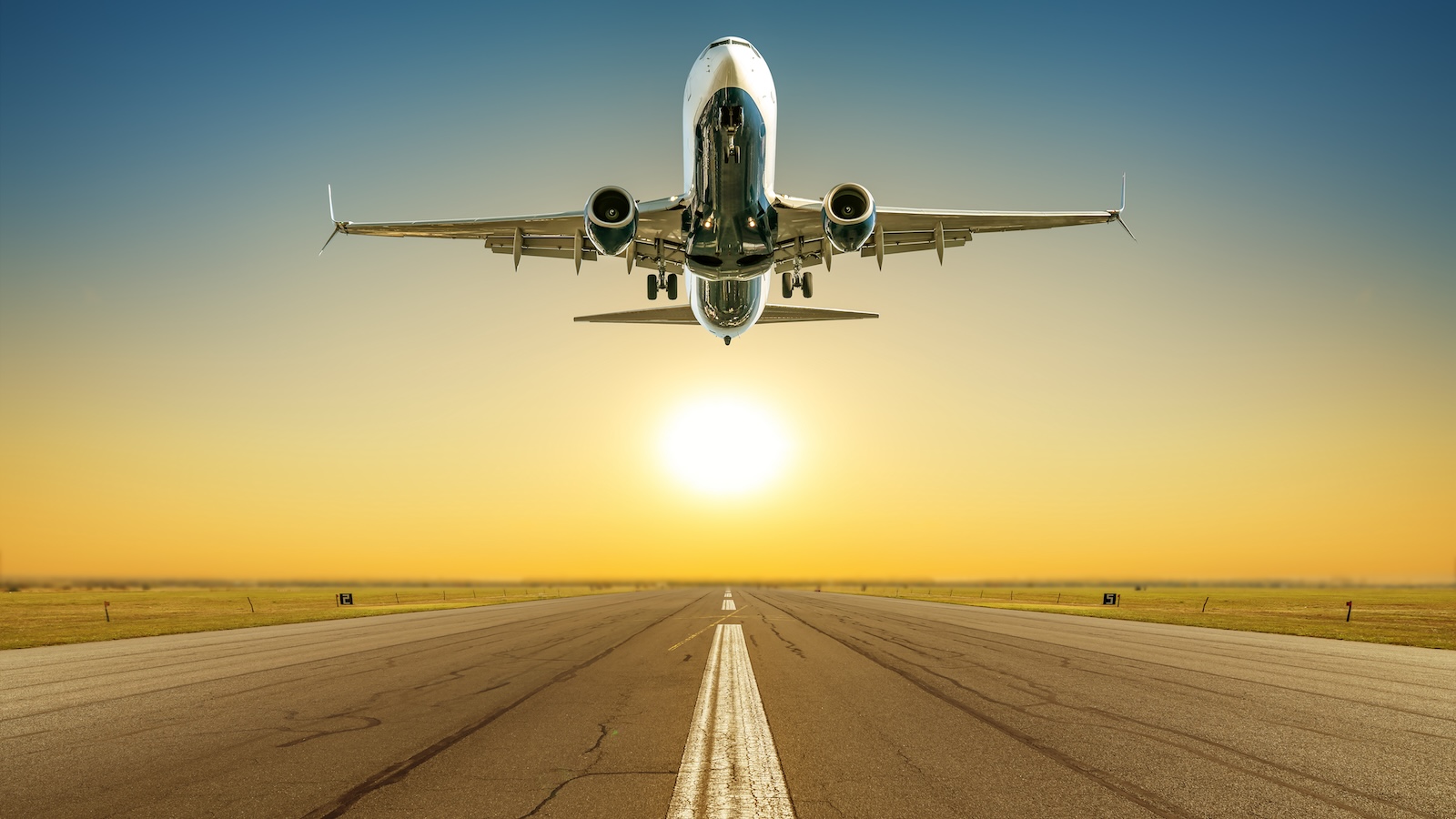 Airplane taking off from a runway at sunset