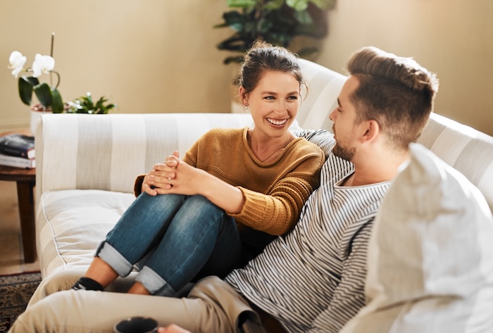 Young couple talking on a coach at home. 